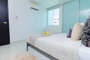 Een moderne slaapkamer met een bed, een raam en een airconditioning.