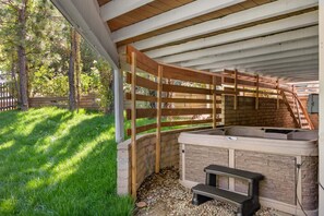 A covered outdoor area with a hot tub, wooden pergola, and a brick wall. - Lake Arrowhead Cabin 3BR | Hot Tub + Lake Access (Lake Arrowhead)