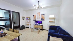 Een moderne woonkamer met een bank, een salontafel, een televisie en een ventilator.