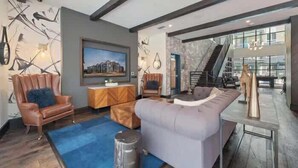 A modern living room with a sectional sofa, a coffee table, and a fireplace. There is a staircase leading to an upper level.