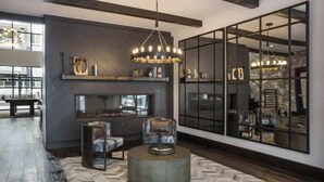 A modern living room with a fireplace, large windows, and a chandelier.