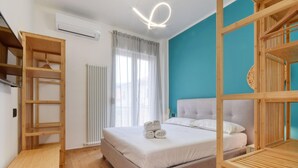 Un dormitorio con cama, radiador, ventana con cortinas y muebles de madera.