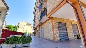 Una calle urbana estrecha con un hilera de edificios de varios pisos, algunos con balcones y contraventanas.