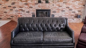 Un sofá de cuero negro en una habitación con pared de ladrillo y chimenea.