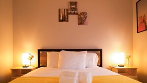 Una habitación de hotel con una cama grande, dos mesitas de noche con lámparas y una pared decorada con cuadros.