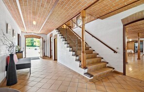 A spacious interior with a brick ceiling, a wooden staircase, and a dining area with chairs and a table. - 7 bedroom stunning home in Grenaa (Grenaa)