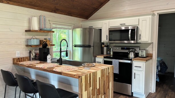 A modern kitchen with wooden cabinetry, stainless steel appliances, and a central island with bar stools.