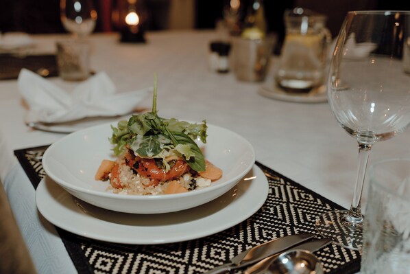 A dining table with a plate of food, a wine glass, and cutlery. - Leopard's Bend Bush Lodge - All Inclusive (Hoedspruit)