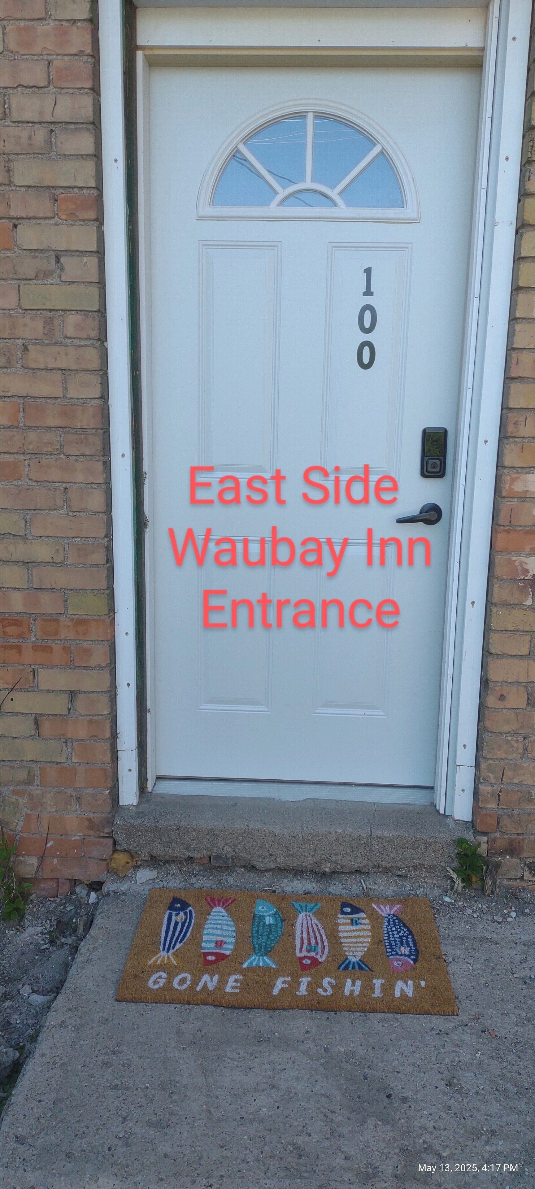 A white door with the address "100" and the text "East Side Waubay Inn Entrance" in red.