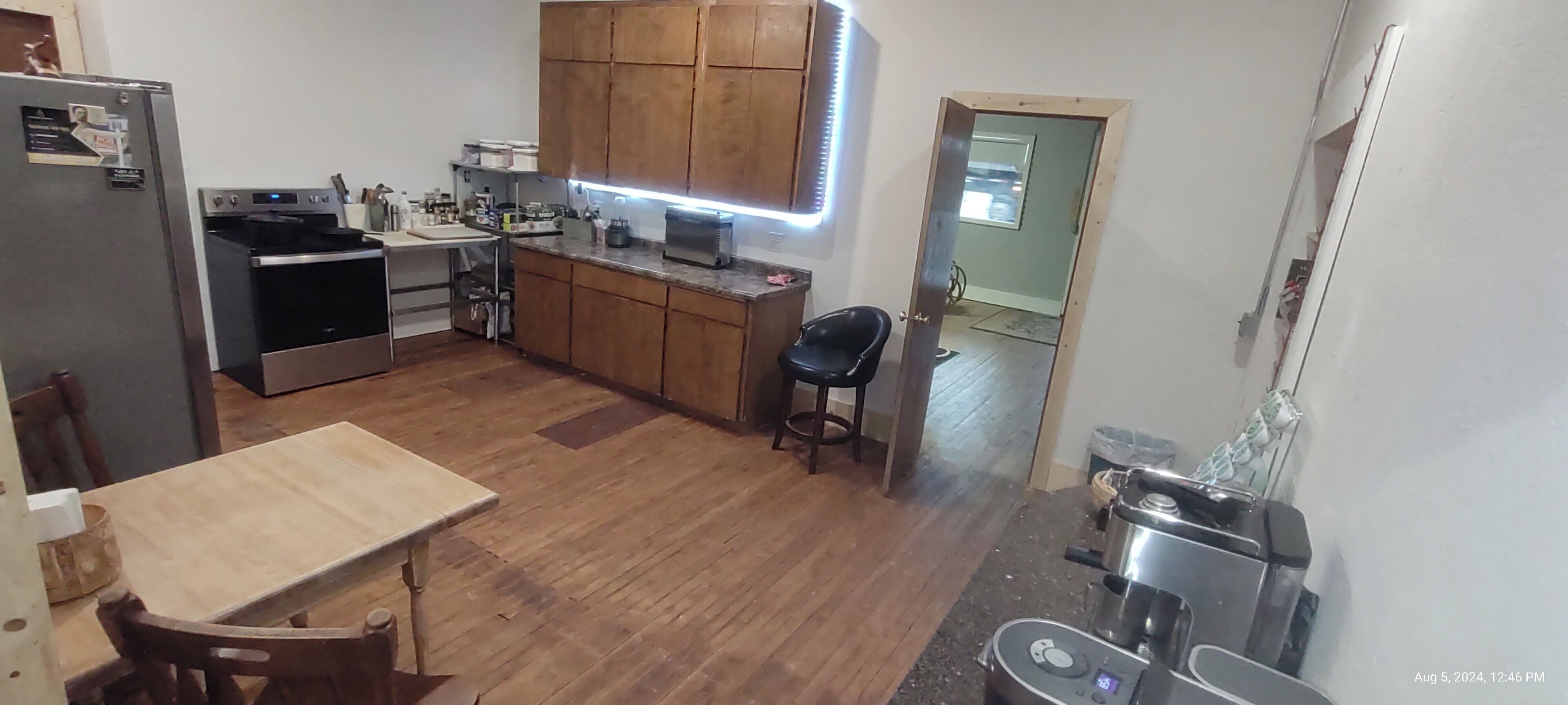 A kitchen with wooden cabinets, a refrigerator, an oven, a sink, and a countertop with various appliances.