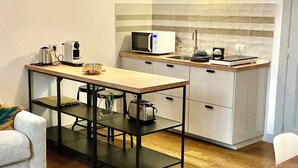 Eine kleine Küche mit Mikrowelle, Toaster und Kaffeemaschine. Es gibt einen Esstisch mit Stühlen und eine kleine Couch.