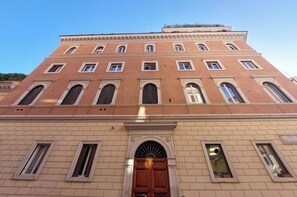 A large, historic building with a symmetrical facade, multiple windows, and a central entrance with a wooden door. - Flatinrome Spanish Steps 2 (Rome)