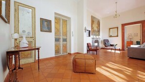 Uma sala de estar ampla, com uma janela grande, lareira e um espaço de estar confortável.