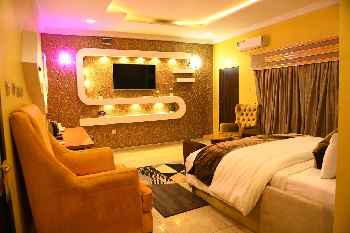 Ein modernes Hotelzimmer mit einem großen Bett, einer Couch, einem an der Wand montierten Fernseher und einem kleinen Tisch.