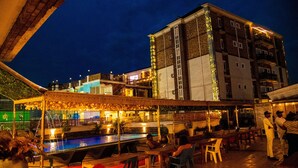 A rooftop bar with a pool, outdoor seating, and a view of a cityscape at night. - Portland Resort Hotel (Port Harcourt)