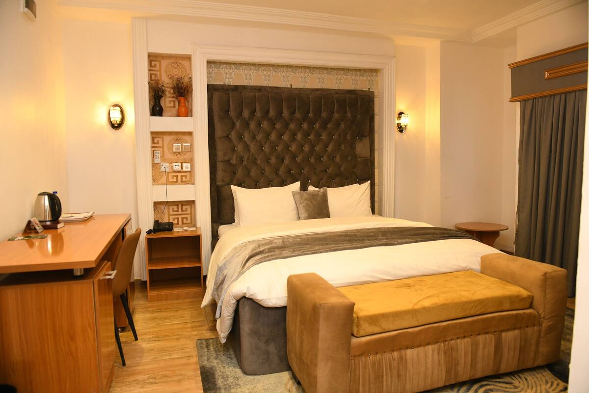 Ein Hotelzimmer mit einem großen Bett, einem Schreibtisch, einem Sessel, einem kleinen Tisch und einer Couch.