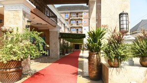 A hotel corridor with a red carpet, potted plants, and a balcony with a wrought iron railing. - Portland Resort Hotel (Port Harcourt)