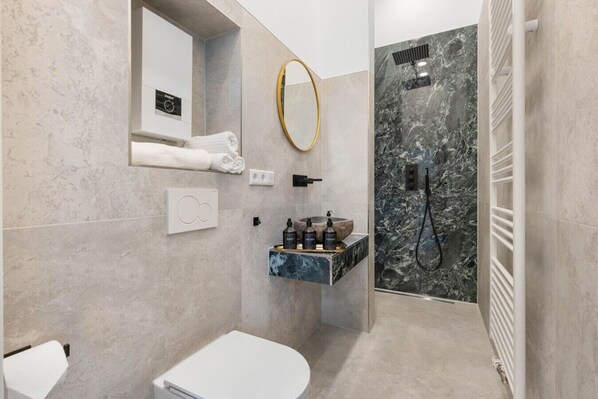 A modern bathroom with a marble shower, a built-in sink with toiletries, and a towel rack. - NEW | LUXUS Suite | Kingbed | Netflix | Center (Augsburg)