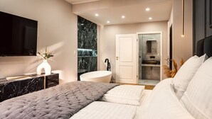 A modern bedroom with a large bed, a vanity with a mirror, and a bathtub. - NEW LUXUS Suite | TWO Kingbeds | Netflix | Center (Augsburg)
