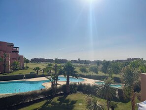 Un resort con piscina, palme e cielo sereno.