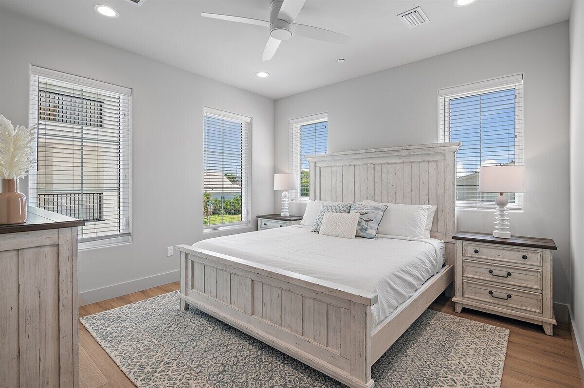 A bedroom with a large bed, two bedside tables, and a ceiling fan.