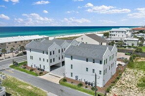 A beachfront hotel with multiple buildings, a road in front, and a clear view of the ocean.