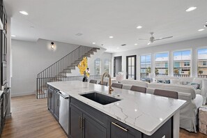 Una cucina moderna con isola in marmo, elettrodomestici in acciaio inossidabile e lavello incassato.