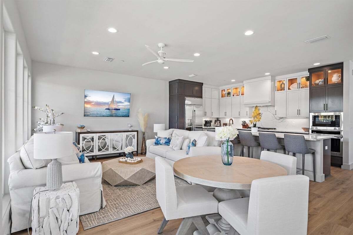 Un salon moderne avec un canapé blanc, une table basse ronde et un coin repas avec des chaises.