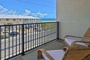 Ein Balkon mit Korbmöbeln und Blick auf die Straße und das Meer.