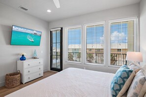 A bedroom with a bed, a dresser, a TV on the wall, and a window with blinds.