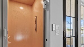 Eine Tür mit Holzvertäfelung im Inneren, einem Metallgriff und einem Glasfenster mit Metallrahmen.