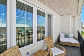 A balcony with wicker furniture and a view of a building.