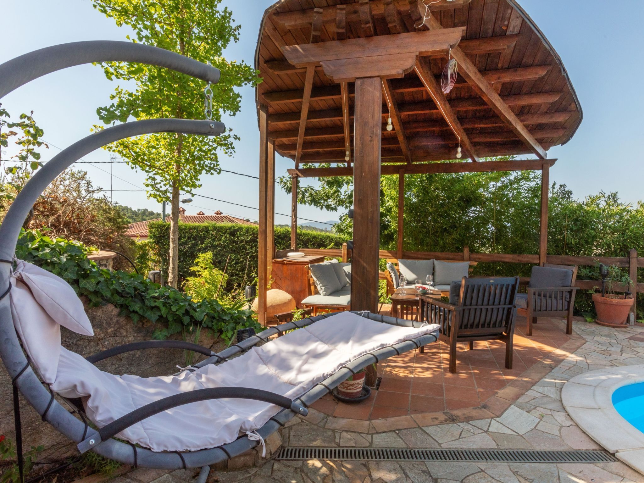 Un espacio de estar al aire libre con techo, piscina, sillones reclinables y una pérgola.