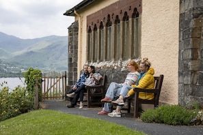 A group of people sitting on a bench outside a building with a stone wall and a window with pointed arches. - Green Beck Cottage Coniston -  a cottage that sleeps 5 guests  in 3 bedrooms (Coniston)