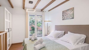 A hotel room with two beds, a balcony with a view, and a painting on the wall. - Your Family Beach Getaway: Pool, BBQ & Ocean at Your Doorstep! (Ligaria)