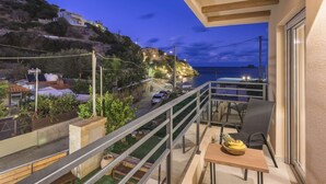 A balcony with a table, chairs, and a bowl of fruit. - Your Family Beach Getaway: Pool, BBQ & Ocean at Your Doorstep! (Ligaria)