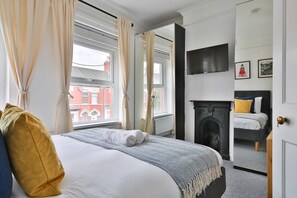 A hotel room with a bed, a fireplace, a TV mounted on the wall, and a view of the outside. - Stunning 2 Bedroom Cardiff Bay House (Cardiff)
