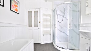 A modern bathroom with a glass shower enclosure, a white bathtub, and a door leading to another room. - Stunning 2 Bedroom Cardiff Bay House (Cardiff)