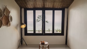 A room with a large window, two wooden chairs, a small table with fruit, and a floor lamp. - Beijo do Vento Pousada (Porto Seguro)