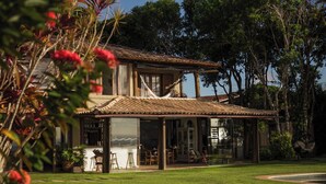 A two-story house with a covered patio, a swimming pool, and a view of the water. - Beijo do Vento Pousada (Porto Seguro)