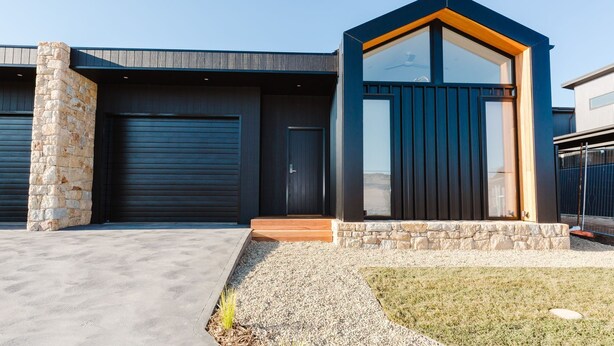 A modern house with a garage, a stone pillar, and a small wooden porch. - 16B Rawson Street - Brand new Build (Jindabyne)