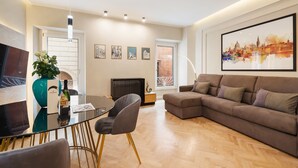 Een moderne woonkamer met een bruine modulaire bank, een eettafel met stoelen, een groot stadsgezicht in een lijst en een radiator.
