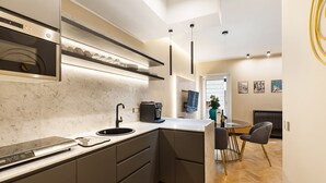 Een moderne keuken met ingebouwde apparatuur, een eethoek met een tafel en stoelen, en een zicht op de woonkamer.