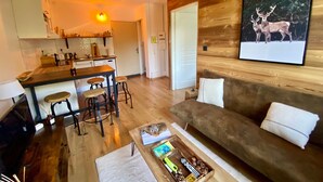 A modern living room with a wooden accent wall, a sofa, and a coffee table. - Cozy T2 Apartment for 3 in Formiguères - Close to Shops and Ski Slopes (Formiguères)