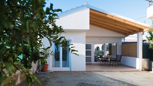 A modern house with a covered patio, a potted plant, and a dining area with chairs and a table. - Apartment with Free Covered Parking (Zadar)