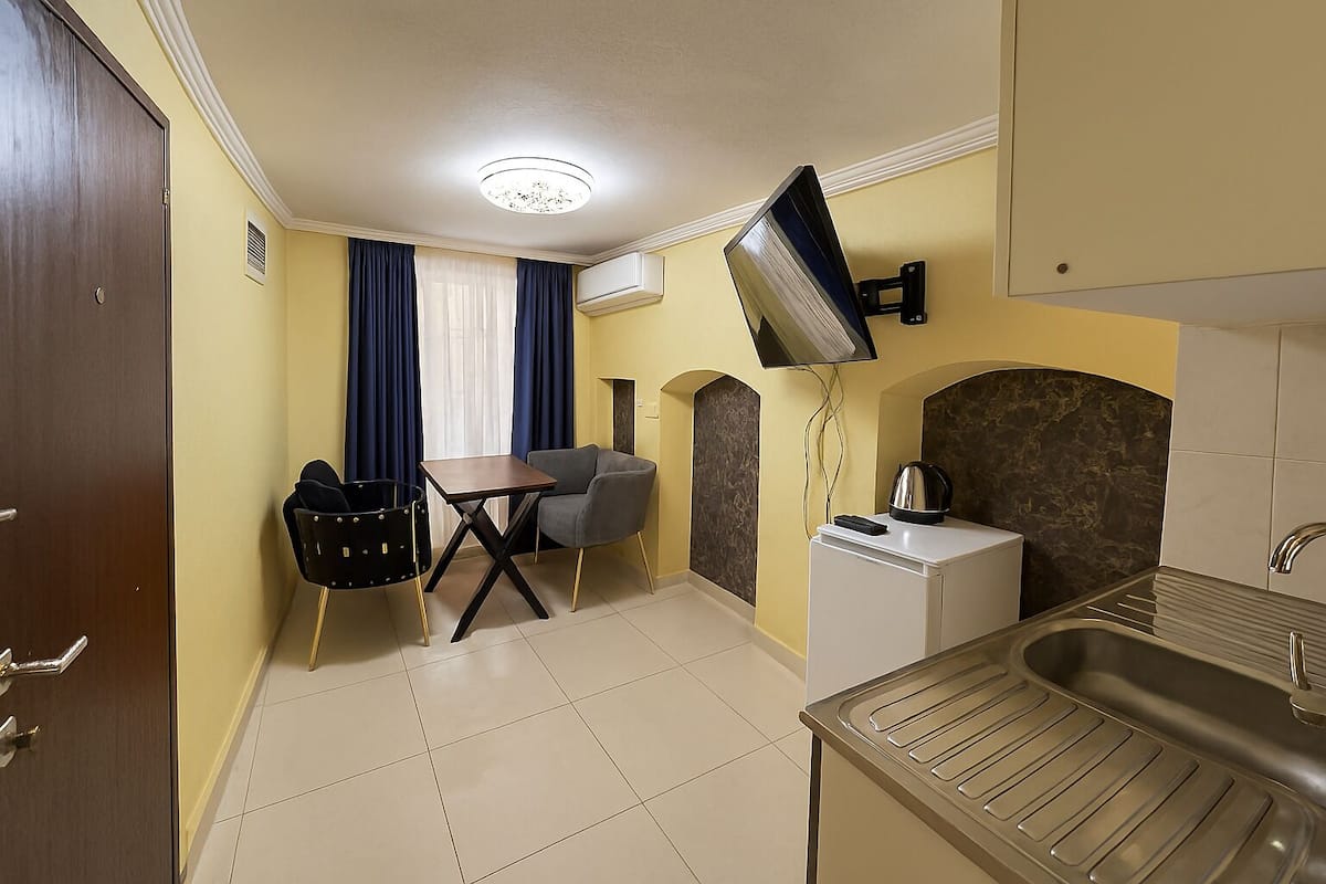A compact kitchen with a sink, a small table, and a chair.