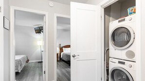 Une chambre d’hôtel équipée d’un lave-linge, d’un lit avec une tête de lit en bois et d’un téléviseur placé dans un coin.