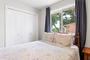 Une chambre à coucher avec un lit, une fenêtre avec des rideaux et une armoire blanche.