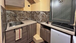A compact kitchen with a sink, a stove, and a refrigerator. - Florence Cave House (Firenze)