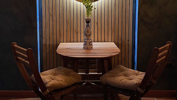 A dining area with a wooden table and chairs, a clock, and two wall-mounted lamps. - Florence Cave House (Firenze)